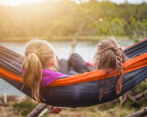 Learn how to lessen the impact of Ddivorce on children so they can be as carefree as these two girls swinging in a hammock on the shore at sunset.