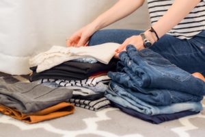 Sorting through your closet like this woman pictured is one of our spring organization tips for single moms.