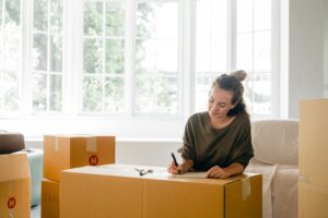 A woman labeling her moving boxes after getting the answers to her question "how can I afford a house after divorce?"