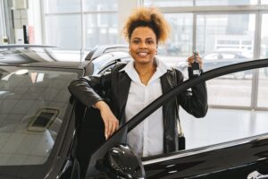 A woman showing off her new car after following our three quick car buying tips for single women.