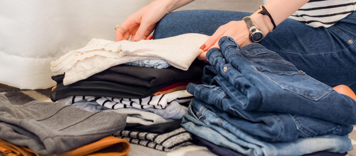 Sorting through your closet like this woman pictured is one of our spring organization tips for single moms.