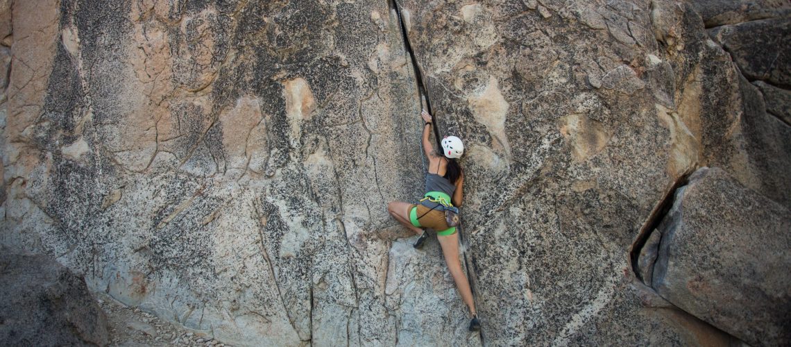 A woman scaling a rock cliff as an example of trying new things after divorce